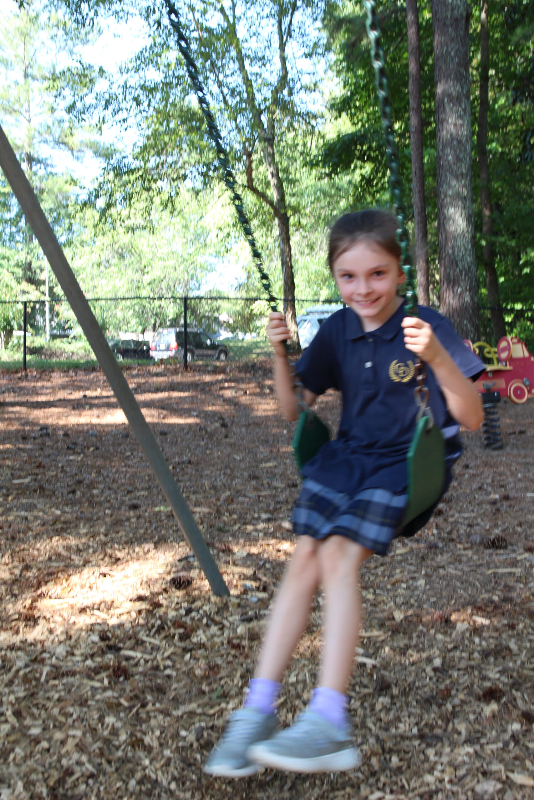 Student swinging on playground at Coram Deo Classical Christian School.